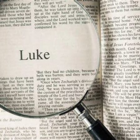 Bible opened to the Book of Luke with a magnifying glass on top